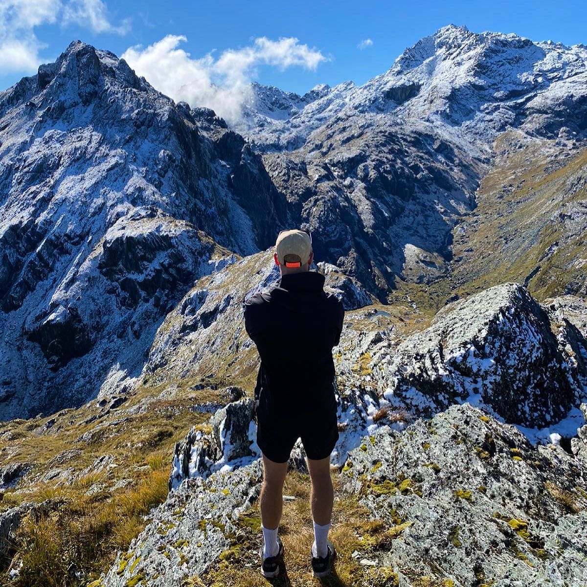 Damian Watson standing in front of mountain peaks